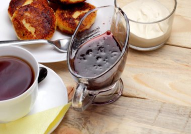 Ülke tarzı, lor güveç veya cheesecake, ekşi krema, yaban mersini reçeli, çay için basit ve lezzetli kahvaltı konsepti. Yakın çekim, metin alanı, doğal ahşap arka plan.