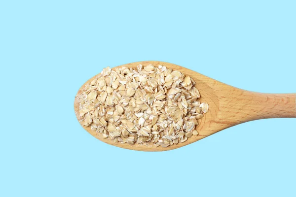 燕麦片在大木勺中分离在浅蓝色背景上 饮食产品 自然色 高对比度 — 图库照片
