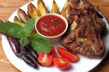 Koyu ahşap bir masada kızarmış kanatları ve pişmiş sebze ile bir tabak üst görünümü, yakın çekim. Rustik yaşam tarzı.