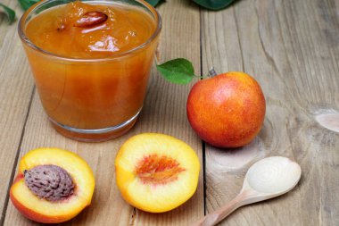 Koyu ahşaptan yapılmış bir masada reçel ile nektarin veya kayısı meyveleri, parlak doğal renkler, yüksek kontrast, koyu anahtar.