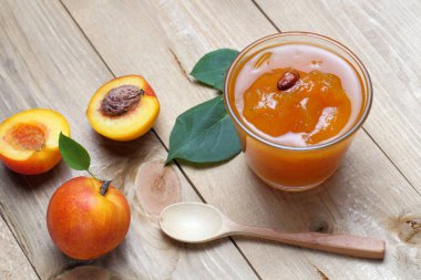 Koyu ahşaptan yapılmış bir masada reçel ile nektarin veya kayısı meyveleri, parlak doğal renkler, yüksek kontrast, koyu anahtar.