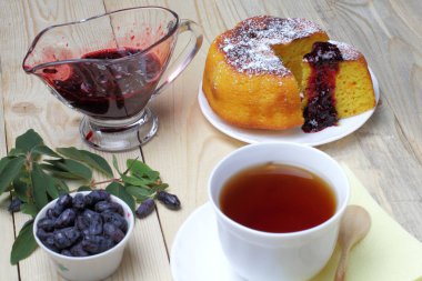 Köy peyniri güveç, taze hanımeli ve reçel, bir fincan çay, basit bir rustik kahvaltı.