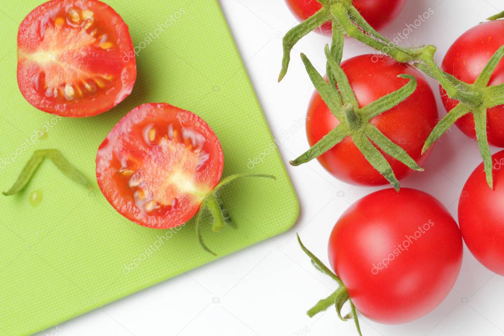 Fresh organic tomatoes with a branch close-up on a white background, bright natural color.