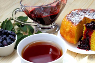 Köy peyniri güveç, taze hanımeli ve reçel, bir fincan çay, basit bir rustik kahvaltı.