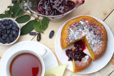 Köy peyniri güveç, taze hanımeli ve reçel, bir fincan çay, basit bir rustik kahvaltı.