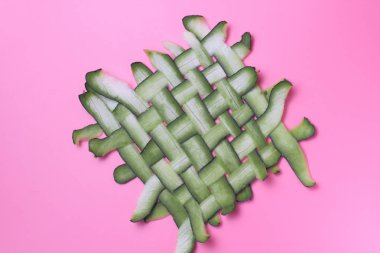 Pembe arka plan üzerinde yeşil liflerden yapılmış hasır yüzey, parlak doğal renkler, yüksek kontrast.