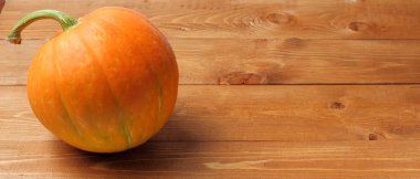 Cadılar Bayramı balkabağı, tatil ana özelliği, rustik ahşap arka plan üzerinde parlak turuncu, geniş görünüm, metin için yer, parlak doğal renk, yüksek kontrast.