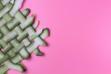 Pembe arka plan üzerinde yeşil liflerden yapılmış hasır yüzey, metin için yer, parlak doğal renkler, yüksek kontrast.