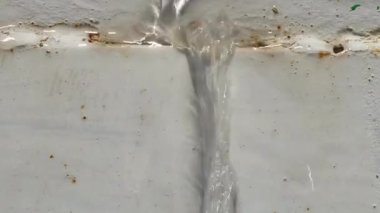 Çelik bir tanktan akan su akıntıları. Parlak akşam güneşi. Yakın plan..