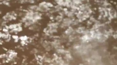 Hareket halindeki su yüzeyinin bulanık görüntüsü. Açık kahverengi arkaplan videosu.