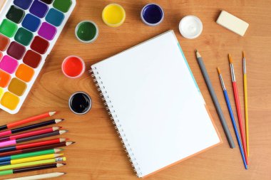 Okul konseptine geri dönelim. Okul gereçleri ve açık bir defter ya da eskiz defteri bir yazı masasında ya da okul masasında, kapatın. Üst görünüm, düz görünüm, metin için yer, kopyalama alanı.