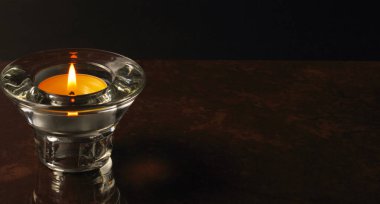 Cam bir şamdanda yanan bir mum küçük bir arka planda, yakın planda. Siyah canlı madde konsepti. Metin için yer, kopyalama alanı.