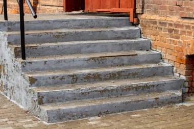 Boyanın soyulduğu beton bir merdiven eski bir tuğla binaya çıkıyor..