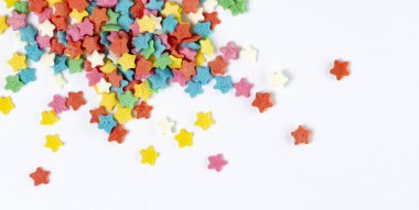 Beyaz yakın plan üzerine dağılmış çok renkli şeker yıldızları. Tatil ya da iyi ruh hali kavramı. Üst görünüm, düz görünüm, metin için yer.