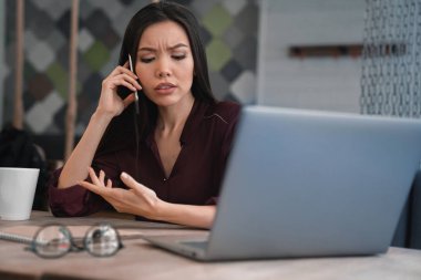 Onun işyerinde oturan ve jest ile bazı iş sorular üzerinde cep telefonu elinde tartışırken meşgul kadın