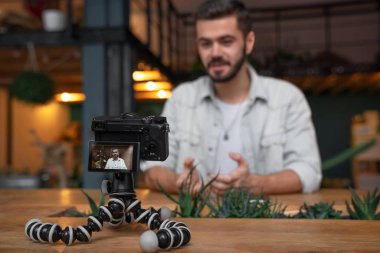 Genç adam yazmak video kamera için onun vlog üçayağa monte. Kameranın bu odaklı gülüp çekici blogger