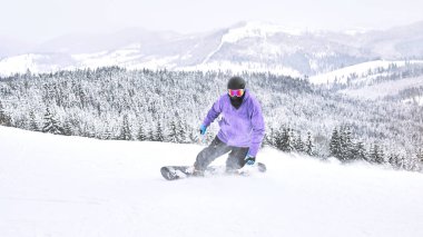 Snowboard onun snowboard binme ve kamera dağlarda polarize gözlük ile onu ve dağlar, orman manzaralı arka planda bakarak                             