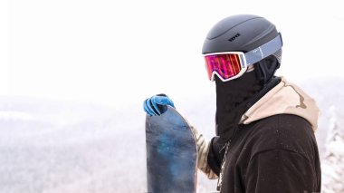 Tepenin üstünde duran ve arka planda dağ ile bir gezintiye seyir snowboard tutun snowboard portre                               