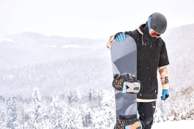 Erkek snowboard onun snowboard yaparken Dağları ile tepe ve arka planda forrest arıyorsunuz                               