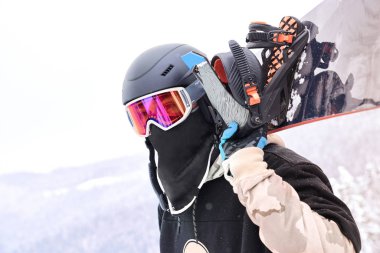  Bu holding adam snowboard atış kapatmak ile kış ahşap arka plan üzerinde uzakta ararken onun omuzlarında snowboard                              