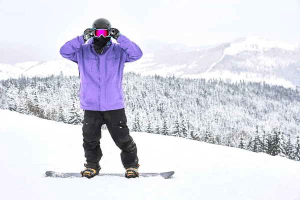 Snowboarder Está Seu Snowboard Endireitando Óculos Olhando Frente Dele Com — Fotografia de Stock