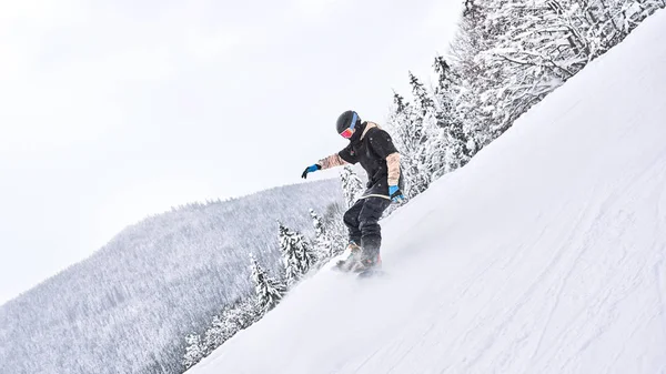 いくつかの動きを作る いくつかの極端な動きしながら 男性スノーボーダーが雪に覆われた丘から乗っています — ストック写真