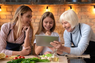 Beyaz aile mutfakta yemek yaparken tablet bilgi bulmaya gülümseyen mutlu