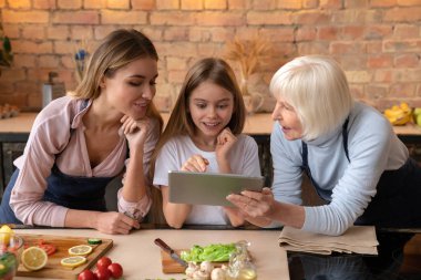 Mutfakta yemek yaparken bazı bilgiler Tablet izlerken mutlu gülümseyen aile önden görünümü