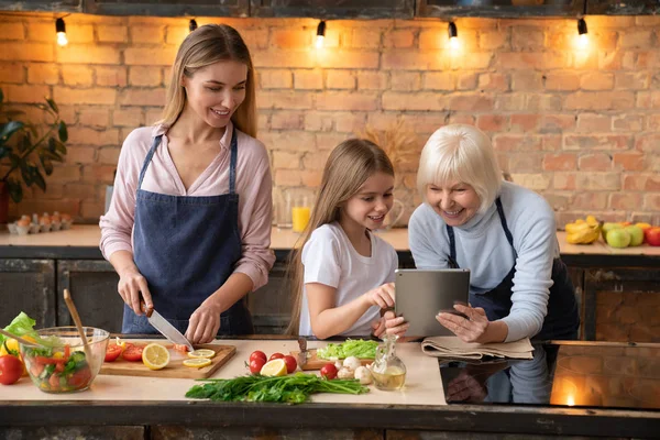 Linda Niña Mostrando Algunos Madre Abuela Tableta Mientras Prepara Verduras — Foto de Stock