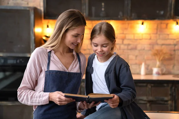 Mulher Bonita Feliz Que Olha Sua Filha Ler Livro Cozinha — Fotografia de Stock