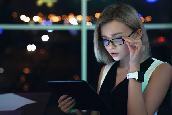Ofis dijital tablet üzerinde çalışan genç iş kadını yakın. Güzel kadın çalışma geç gece ofis üzerinde SmartWatch ile bir masada oturan — Stok fotoğraf