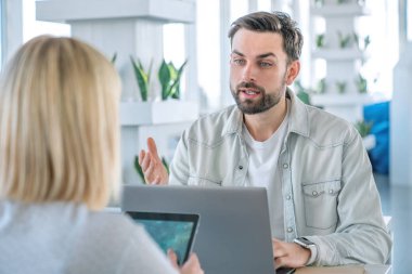 Bir kafede dizüstü bilgisayar üzerinde çalışan arkadaşlar. Dizüstü bilgisayar ve dijital tablet ile bir sehpa da oturan iş ortakları