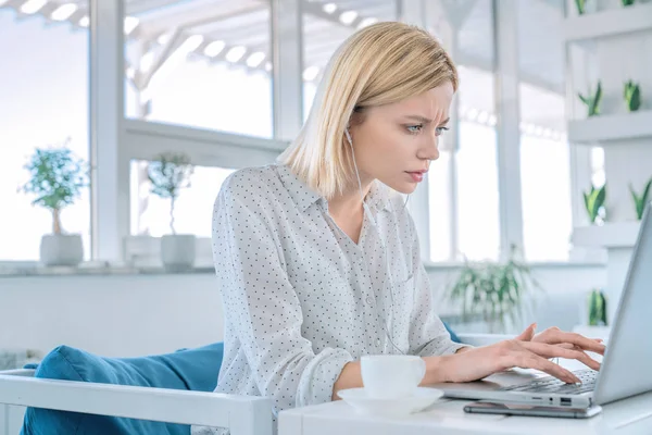 İş yerinde otururken dizüstü bilgisayarda çalışan iş kadını fotoğrafı, üzerinde kahve ve cep telefonu yla — Stok fotoğraf
