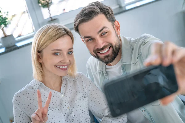 Gülümseyen çift, kafede otururken cep telefonu yla selfie çekiyor. Kafede mutlu anları paylaşan kadın ve erkek — Stok fotoğraf