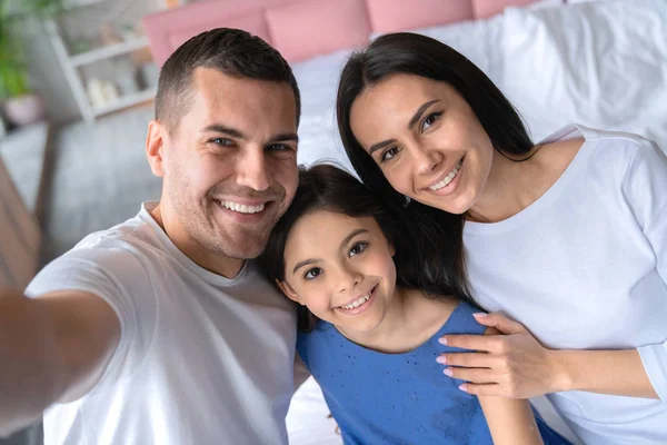 Mutlu genç adam ailesiyle selfie çekiyor. Aile yatak odasında durup evde selfie çekiyor — Stok fotoğraf