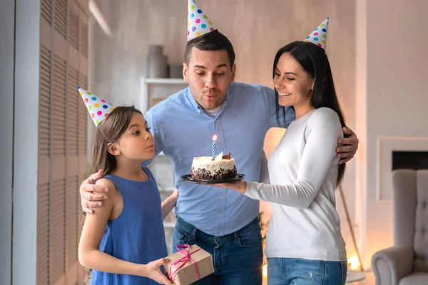 Happy father blowing candles on cake while celebrating birthday