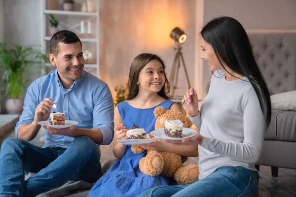 Feliz familia joven comiendo juntos pastel en casa. Familia alegre — Foto de Stock