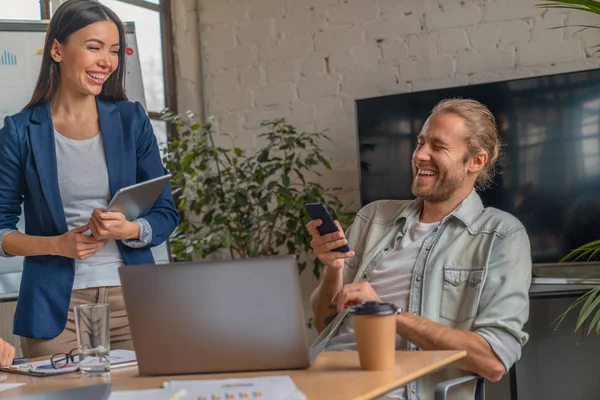 Prise de vue de professionnels des affaires riant lors d'une réunion au bureau. Partenaires d'affaires avec smartphone dans les mains s'amuser dans le bureau de coworking — Photo