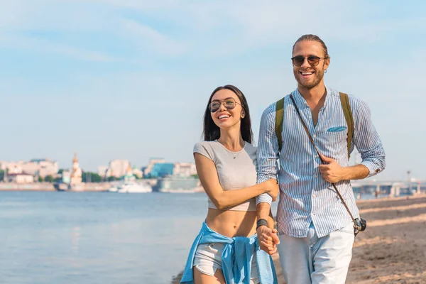 Close up tiro de casal jovem romântico andando na praia da cidade. Homem e mulher desfrutando de um dia na praia . — Fotografia de Stock