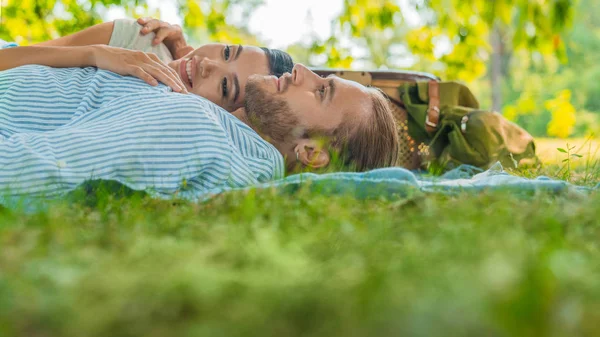 Casal jovem deitado juntos em cobertor de piquenique. Homem e mulher relaxando juntos no parque . — Fotografia de Stock