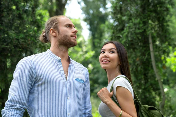 Jovem homem e mulher na floresta olhando para cima e sorrindo. Casal bonito passar tempo juntos na floresta . — Fotografia de Stock