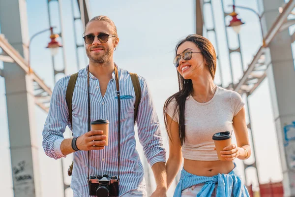 Foto de jovem casal feliz na rua andando bebendo café e conversando uns com os outros — Fotografia de Stock