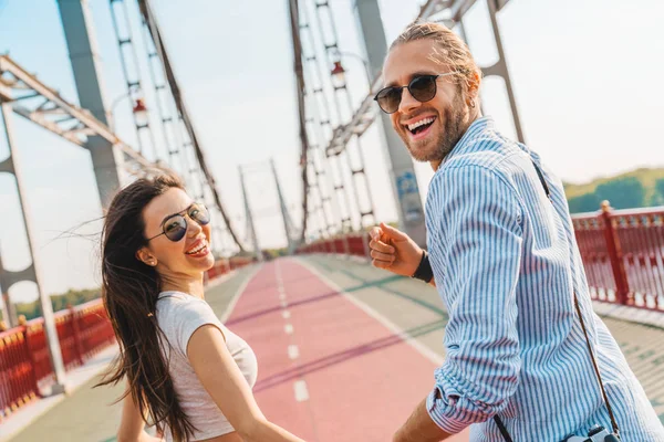 Linda feliz jovem casal férias em roupas casuais de mãos dadas enquanto corre ao ar livre — Fotografia de Stock