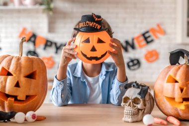 Küçük çocuk Cadılar Bayramı 'nda evde balkabağıyla eğleniyor.