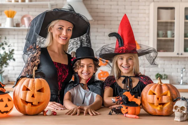 Volwassen moeder en kinderen staan in kostuums in de keuken en kijken in de camera — Stockfoto