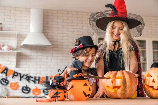 A kisfiú a tinédzser nővérével szórólapot készít a Halloween-i díszített konyhában. — Stock Fotó