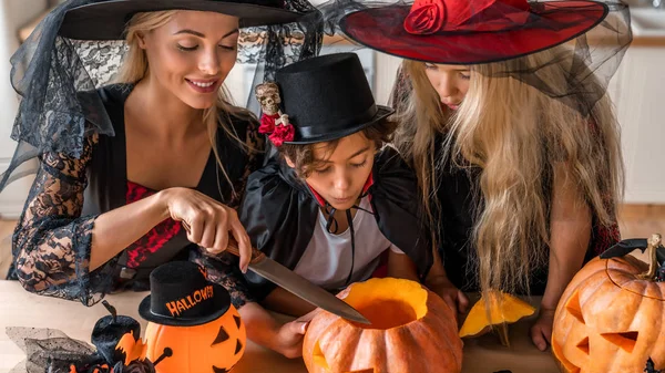 Família feliz preparando o jackolantern na cozinha decorada em casa — Fotografia de Stock