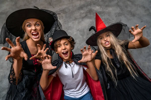 Família feliz se divertindo e assustador com o olhar na câmera em pé sobre fundo cinza — Fotografia de Stock