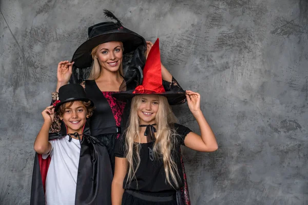 Crianças alegres em trajes de Halloween posando sobre fundo cinza — Fotografia de Stock