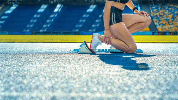 Vista lateral recortado tiro de corredor femenino sentado en la línea de salida en la pista de atletismo —  Fotos de Stock
